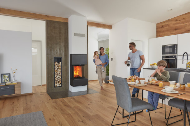 Eine Familie im Wohnzimmer vor einem modernen Schiedel KINGFIRE Ofensystem beim Frühstück